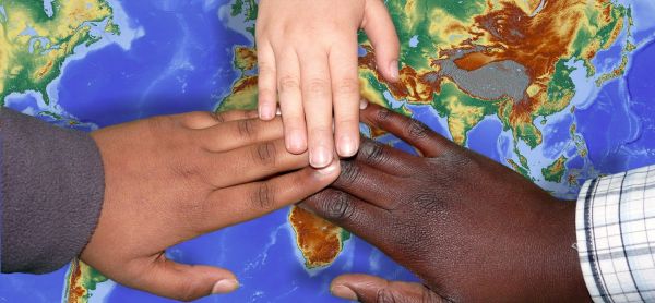 Dłonie w różnych kolorach skóry na mapie świata