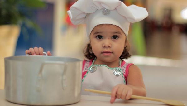 Dziecko w czapce kucharza przy stole z garnkiem